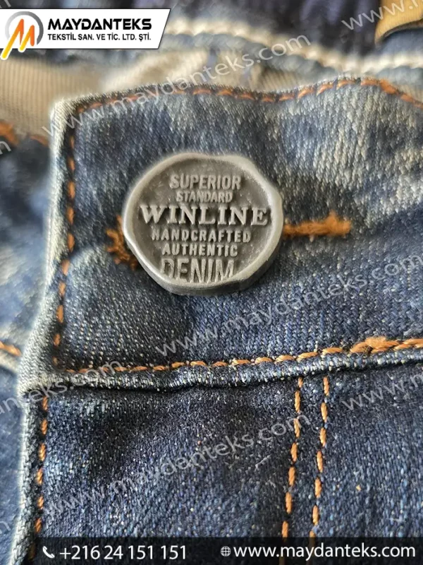 Bouton métal robuste monté sur jeans en denim, fixation solide pour textile épais