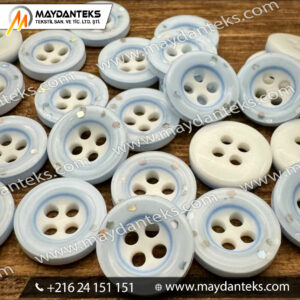 Bouton couture bleu nacré à 4 trous avec paillettes argentées (résine polyester).